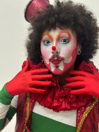 Personagem de figurino verde, luvas e gola vermelhas
